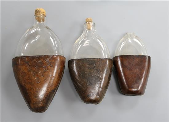 Three 18th century and later leather cased glass flasks, largest 20cm